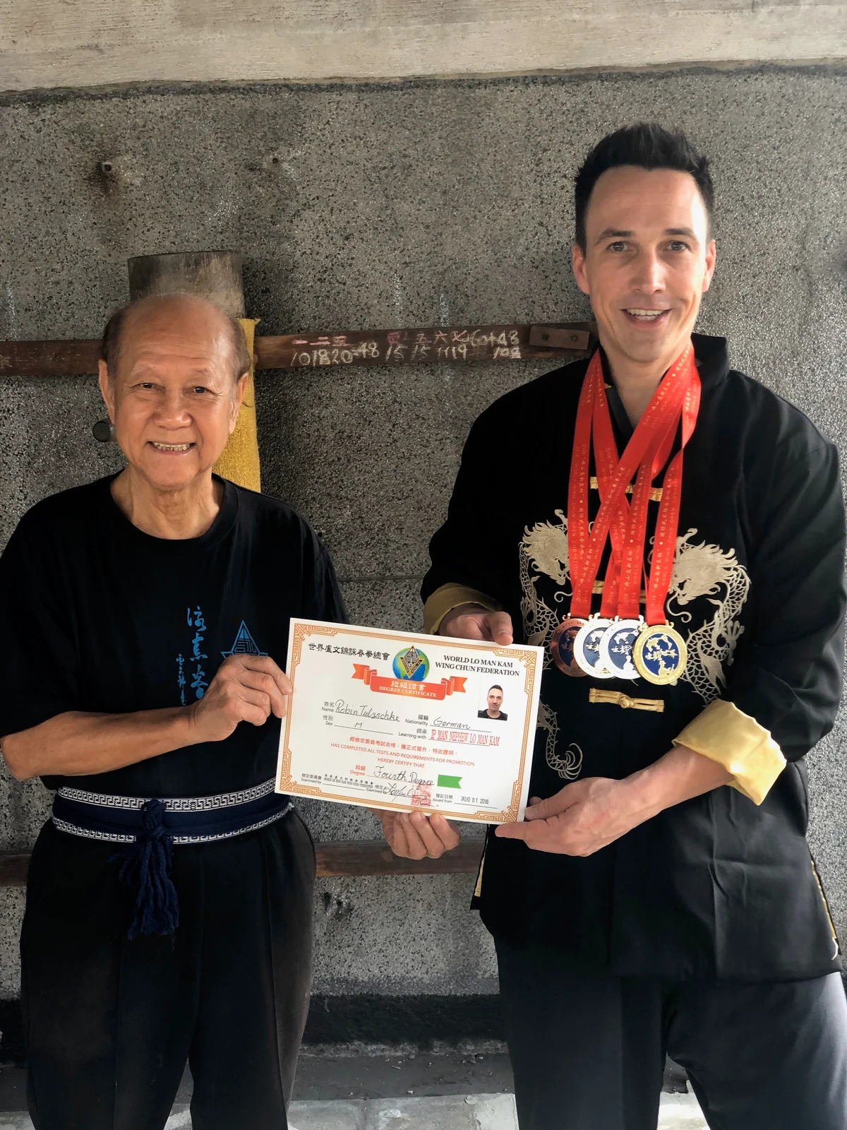 Lo Man Kam mit Robin, vier Medaillen aus Foshan und der Urkunde zum vierten Meistergrad
